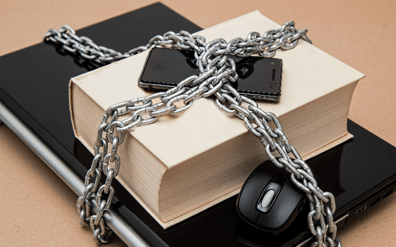 laptop, mouse, phone, and book chained up