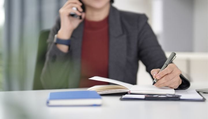 A woman taking notes and talking on the phone