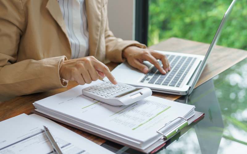 A woman using a calculator and laptop