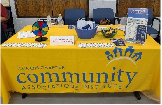 A Community Associations Institute expo booth with a spin wheel and brochures